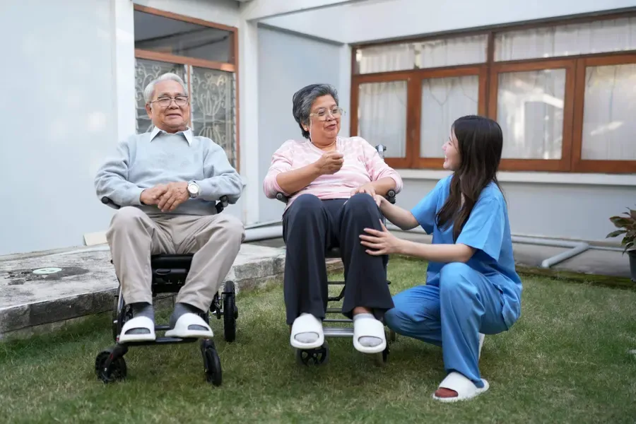 A caregiver spending time with seniors in a sunny garden